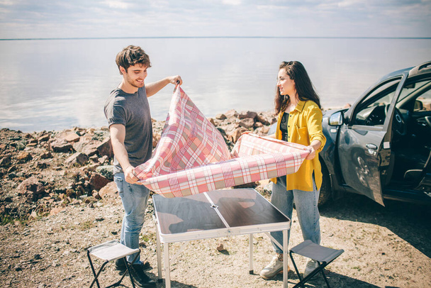 Picnic near the water. Happy family on a road trip in their car. Man and woman are traveling by the sea or the ocean or the river. Summer ride by automobile. - Photo, Image