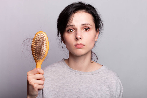 sad woman with a comb in her hands, hair loss problem - Photo, Image