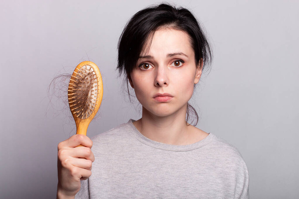 sad woman with a comb in her hands, hair loss problem - Foto, Bild