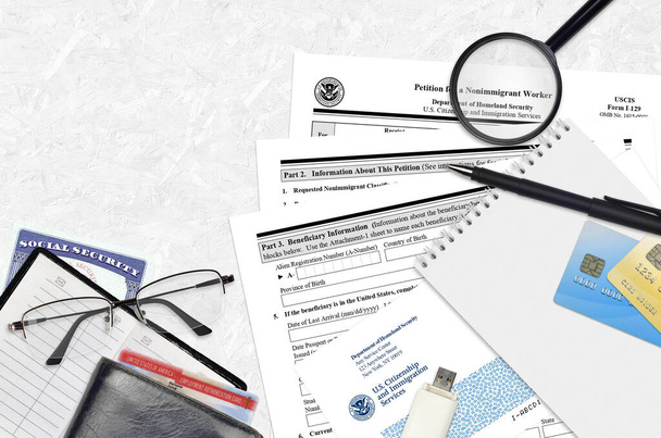 移民以外の労働者のためのUSCISフォームI-129請願書は、平らなレイアウトオフィステーブルにあり、記入する準備ができています。アメリカ。市民権と移民サービスの書類作成コンセプト。トップ表示 - 写真・画像