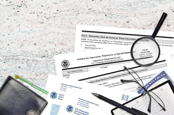 USCISフォームI-360アメリカ人、未亡人、または特別な移民のための請願書は、平らなレイアウトのオフィステーブルにあり、記入する準備ができています。アメリカ。市民権と移民サービスの書類作成コンセプト。トップ表示 - 写真・画像