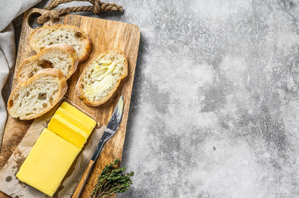 Farm butter and fresh baguette with butter. Gray background.Top view. Copy space. - Фото, зображення