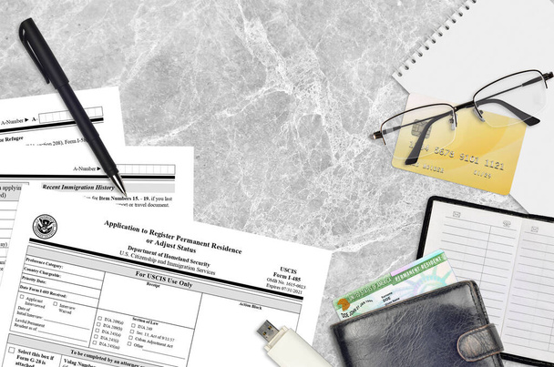 USCIS form I-485 Application to register permanent residence or adjust status lies on flat lay office table and ready to fill. U.S. Citizenship and Immigration services paperwork concept. Top view - Photo, Image