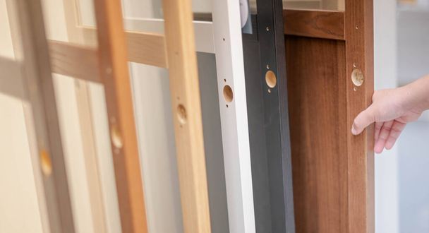 Mão feminina escolhendo a porta da placa de madeira para construirnas portas interiores dentro da casa, para a preparação da decorar em conceito de casa nova
.  - Foto, Imagem