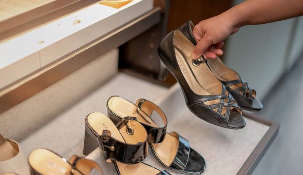 購入する決定のための引き出し棚の革の靴を選択する女性の手、ファッションとショッピングのコンセプト.  - 写真・画像