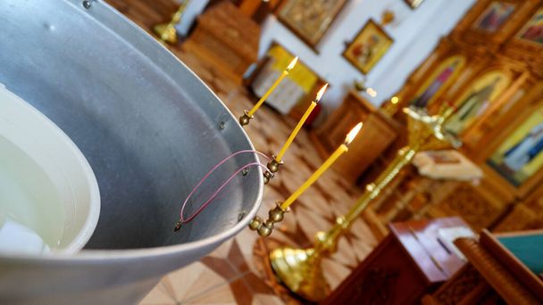 Baptismal font in a ortodoxal church . Accessories for the christening of children with cross and candles. - Photo, Image