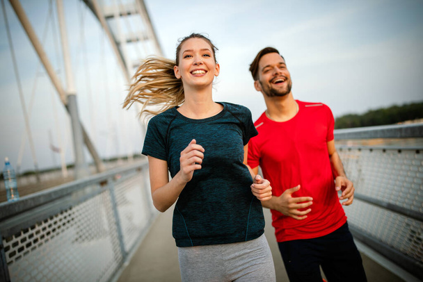 Sport couple. Young man and woman jogging outdoor living healthy life - Fotó, kép