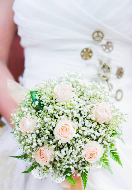 Strauß in den Händen der Braut auf dem Hintergrund des Uhrwerks. Hochzeit im Stil des Steampunk - Foto, Bild