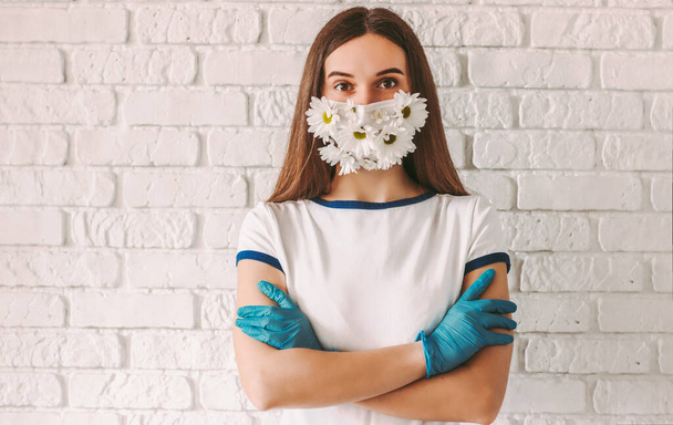 Portrait young confident woman doctor in summer medical face mask keep arms crossed. Happy girl wearing latex medical gloves and protective face mask with flowers. Spring allergy, COVID-19 protection - Фото, изображение