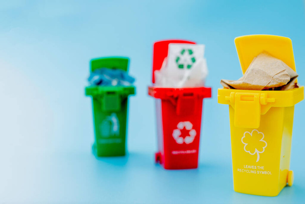 Yellow, green and red recycle bins with recycle symbol on blue background. Keep city tidy, Leaves the recycling symbol. Nature protection concept. - Foto, Imagen