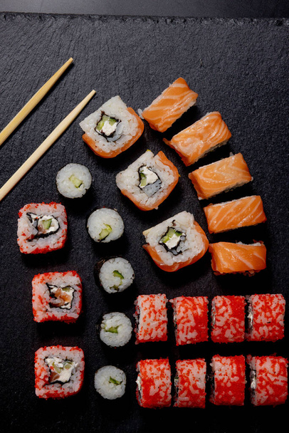 Set of sushi roll on black slate background food fish philadelphia japanese salmon delicious sushi rice cucumber meal traditional wasabi fresh healthy gourmet raw cuisine. - Fotó, kép