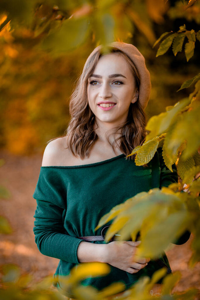 Beautiful girl walking outdoors in autumn. Smiling girl collects yellow leaves in autumn. Young woman enjoying autumn weather - Fotoğraf, Görsel