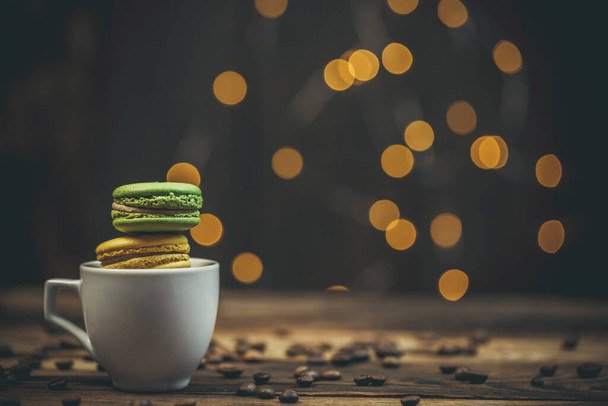Biscoitos macaroon saborosos com café em uma mesa de madeira na cor morna com belo bokeh
 - Foto, Imagem