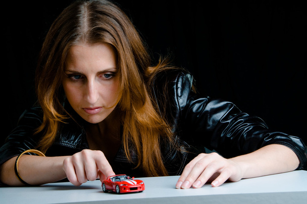 Hot girl playing with a model of the red sport car. - 写真・画像