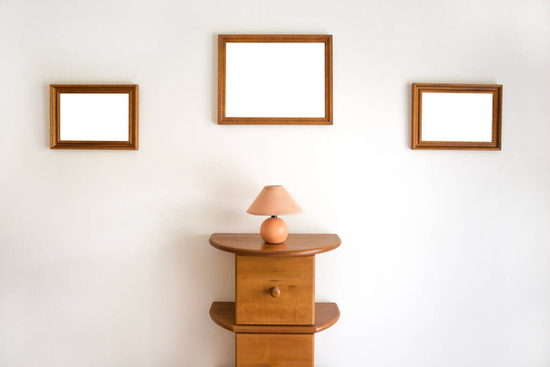 Cornici di legno vuote su una parete con un comò - Foto, immagini