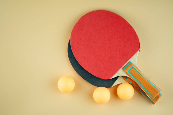 Racchette da ping pong nere e rosse e tre palline arancioni su sfondo arancione - Foto, immagini