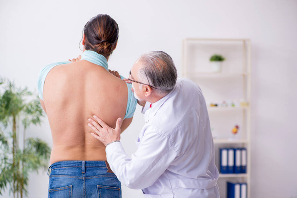 Joven hombre lesionado de espalda visitando experimentado médico masculino
 - Foto, imagen