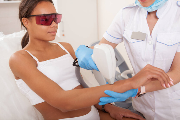 Lovely African woman getting laser hair removal on her arms at beauty salon - Photo, Image