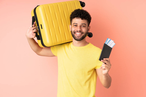 Nuori marokkolainen mies eristetty vaaleanpunainen tausta lomalla matkalaukku ja passi - Valokuva, kuva
