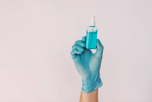 Male nurse hand in medical glove hold sanitizer bottle isolated on white background. Closeup man doctor in protective glove with antibacterial gel dispenser. Personal hygiene, COVID-19 coronavirus - Zdjęcie, obraz
