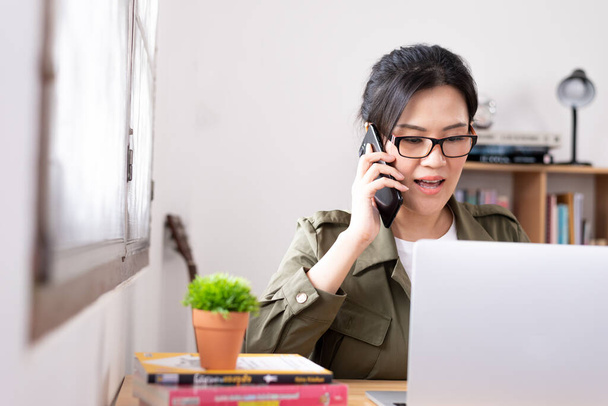 Moderne jonge Aziatische vrouw werken vanuit huis en praten met een partner over haar bedrijf. - Foto, afbeelding