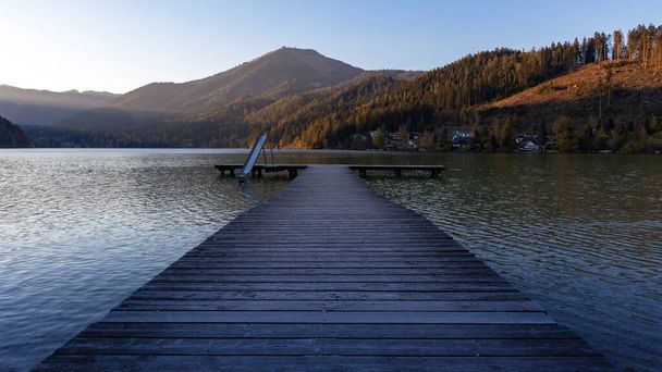 Erlaufsee - horské jezero na úpatí Alp v Dolním Rakousku. Dřevěné molo vedoucí od břehu jezera ke středu. Nechali děti sklouznout do vody. V pozadí alpských kopců  - Fotografie, Obrázek