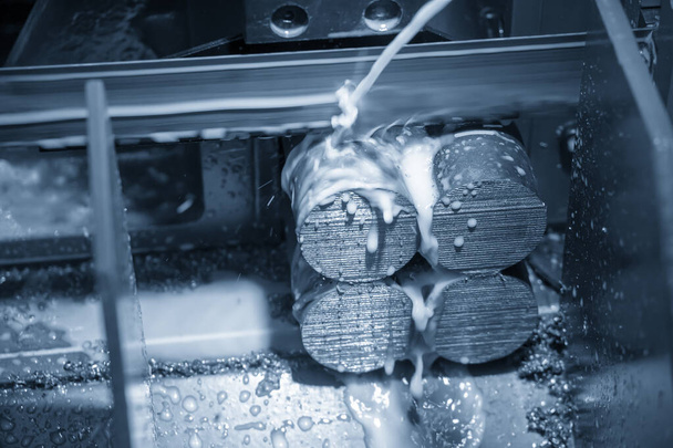 Die automatische Bandsäge schneidet die Metallstange. Der Werkzeugmaschinenbetrieb mit flüssigem Kühlmittel. - Foto, Bild