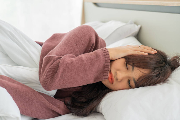 gyönyörű ázsiai nők fejfájás és alszik az ágyban - Fotó, kép