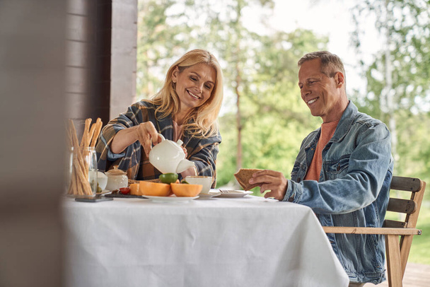 Happy mature spouses having tea with toasts - Zdjęcie, obraz