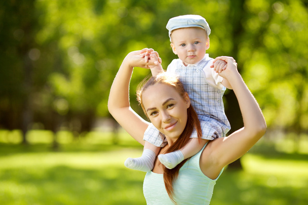 Cute little baby in the park with mother on the grass. Sweet bab - Фото, изображение