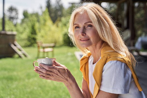 Cheerful woman enjoying hot drink among nature - Photo, image