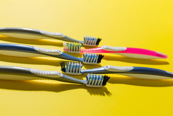 five multi-colored toothbrushes lie on a yellow background. caries prevention. dental clinic. dentistry. dental health. - Photo, Image