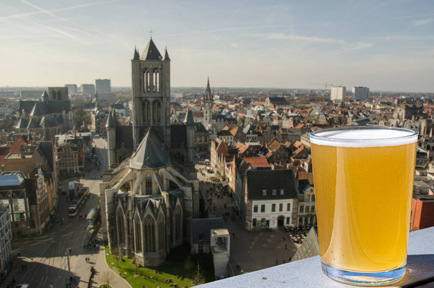Ein Glas leichtes belgisches Bier vor dem Blick auf die große Kathedrale in Gent, Belgien. Blick von oben auf Gent, Belgien - Foto, Bild