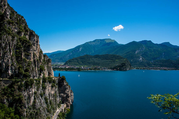 beautiful view of Lake Garda from the Ponale road, with the blue sky, sailing boats, and the green of the lush mountains of Trentino Alto Adige - Photo, Image