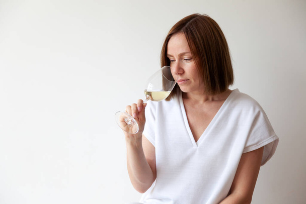 Caucasian brunette girl sommelier holding glass of white wine - Foto, Bild