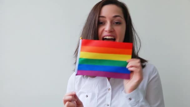 Krásná kavkazská lesbická dívka s LGBT duhovou vlajkou izolované na bílém pozadí vypadá šťastně a vzrušeně. Mladá žena, portrét Gay Pride. Rovná práva pro komunitní koncept lgbtq - Záběry, video
