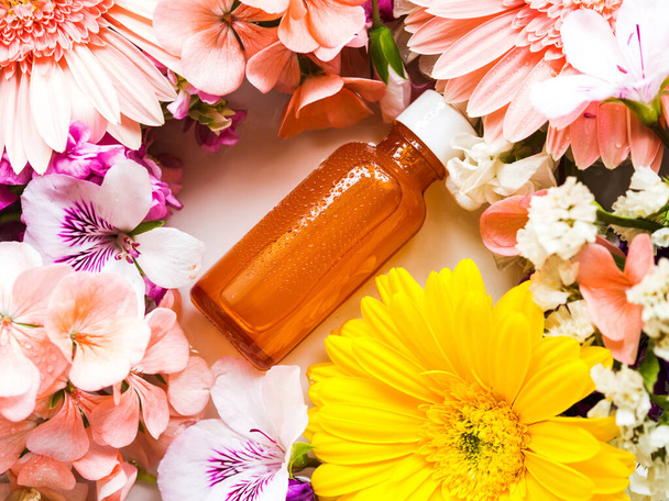 Siero per la cura della pelle in bottiglia arancione con fiori - Foto, immagini