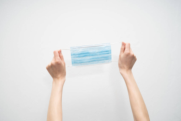 kéz tartsa eldobható védőmaszk fehér alapon - Fotó, kép