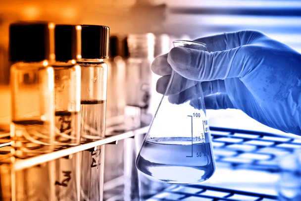 Frasco en mano científica con cristalería de laboratorio en laboratorio, concepto de investigación y desarrollo químico científico
.  - Foto, imagen