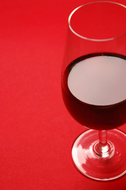 Vörösbort tartalmazó borospohár vörös alapon - Fotó, kép