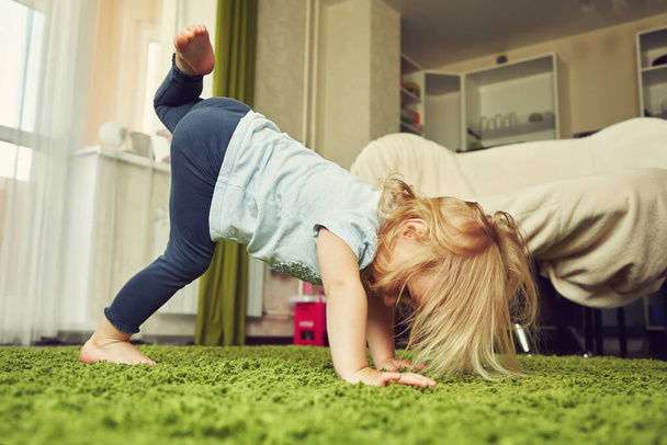 funny little girl doing yoga. child playing at home. - Photo, image