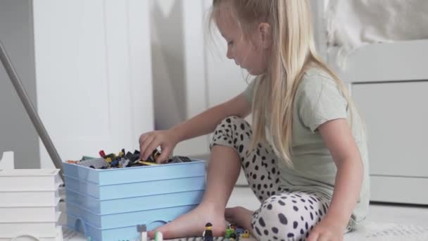 Ein kleines Mädchen sammelt einen Designer aus Kleinteilen im Spielzimmer - Filmmaterial, Video