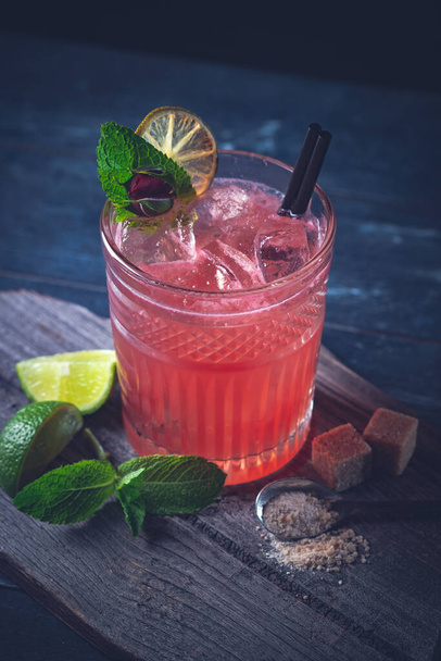Roter Cocktail mit Saft, Grenadine, Eis, Minze und Limette auf Glas. Erdbeermojito - Foto, Bild