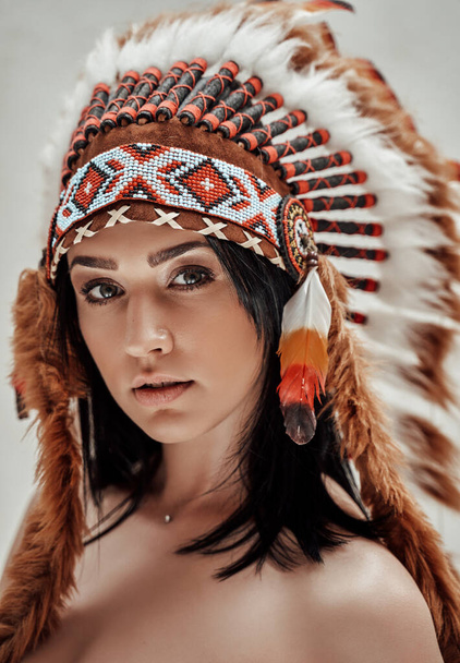 Sexy mayan mulher chefe vestindo cobertura para a cabeça tribal enquanto posando em um apartamento brilhante
 - Foto, Imagem