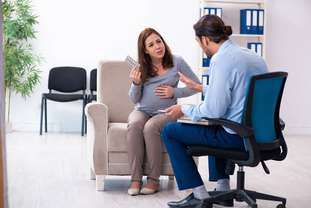 Zwangere vrouw op bezoek bij jonge mannelijke psycholoog - Foto, afbeelding