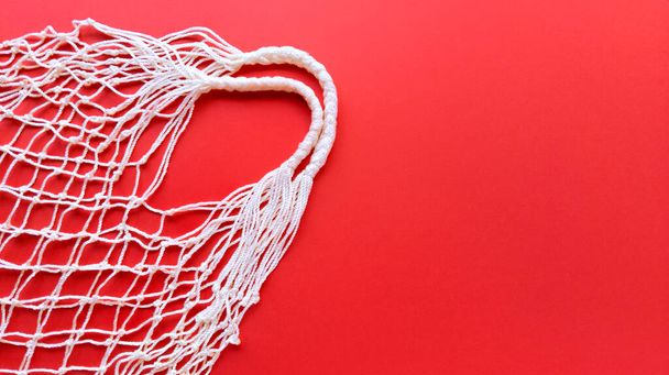 White string cotton eco bag on red background. Simple flat lay with copy space. Ecology zero waste concept. Stock photo. - Fotografie, Obrázek