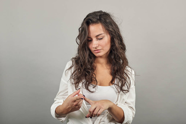 Young attractive woman, dressed white blouse, touches her fingers, manicure - Fotografie, Obrázek