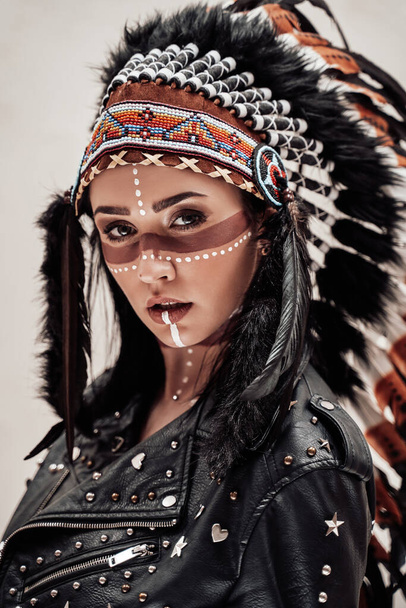 Mulher atraente posando em estúdio e vestindo cobertura para a cabeça tribal e maquiagem oriental
 - Foto, Imagem