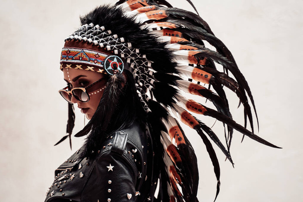 Modello nativo americano che guarda da dietro, indossa giacca di pelle e copricapo in piuma - Foto, immagini