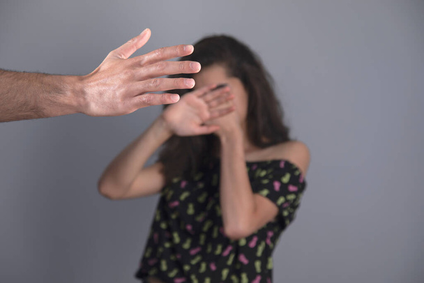 angry man beating sad woman on grey background - Foto, Imagen